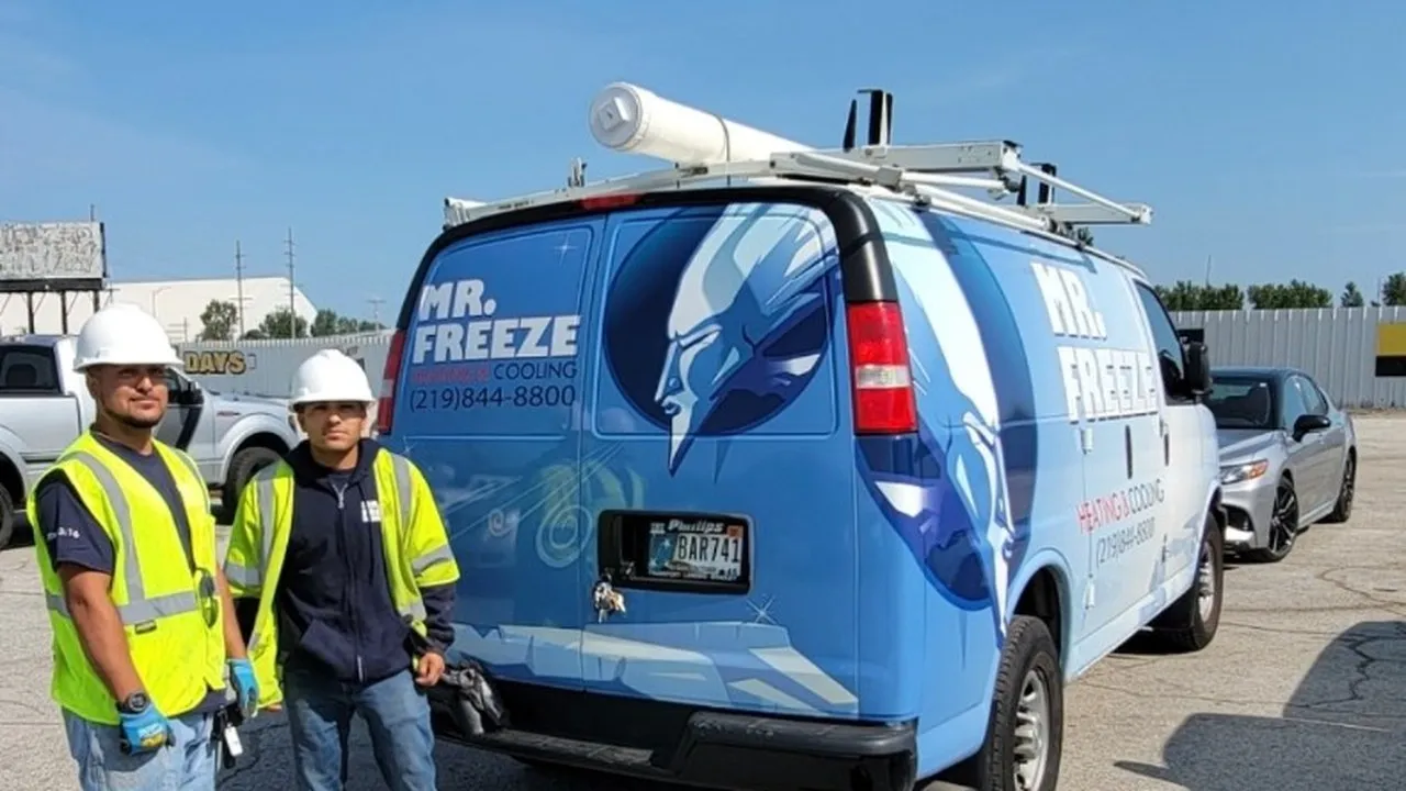 Two Mr. Freeze technicians in high-visibility vests beside their branded service van in Northwest Indiana