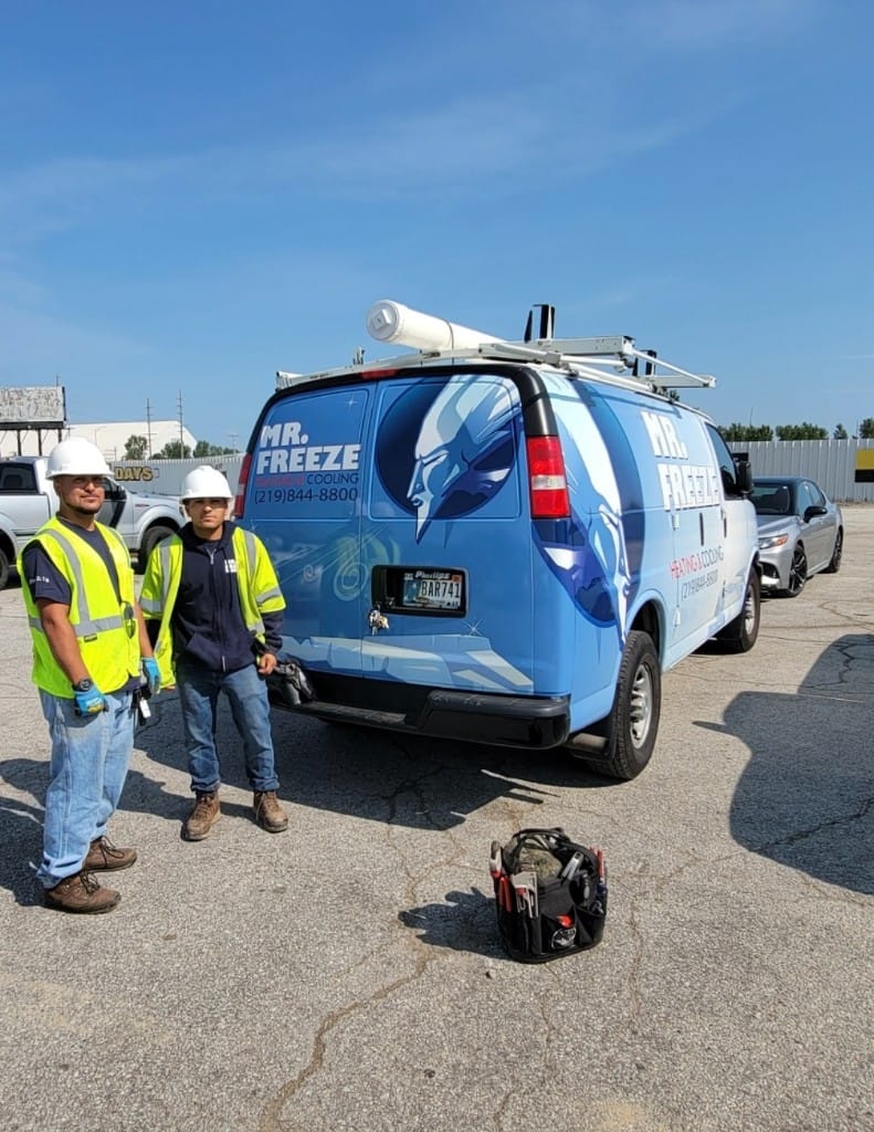 Two Mr. Freeze technicians in high-visibility vests standing beside their branded service van in Northwest Indiana